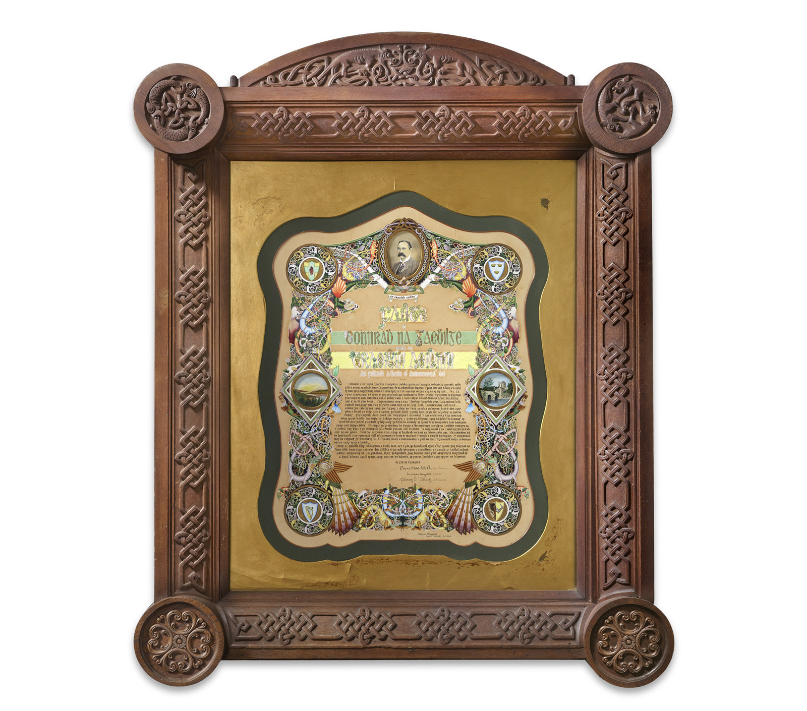 Framed illuminated text with ornate Celtic-style borders, featuring a central portrait, decorative symbols, and detailed text surrounded by intricate knotwork carvings on the wooden frame.