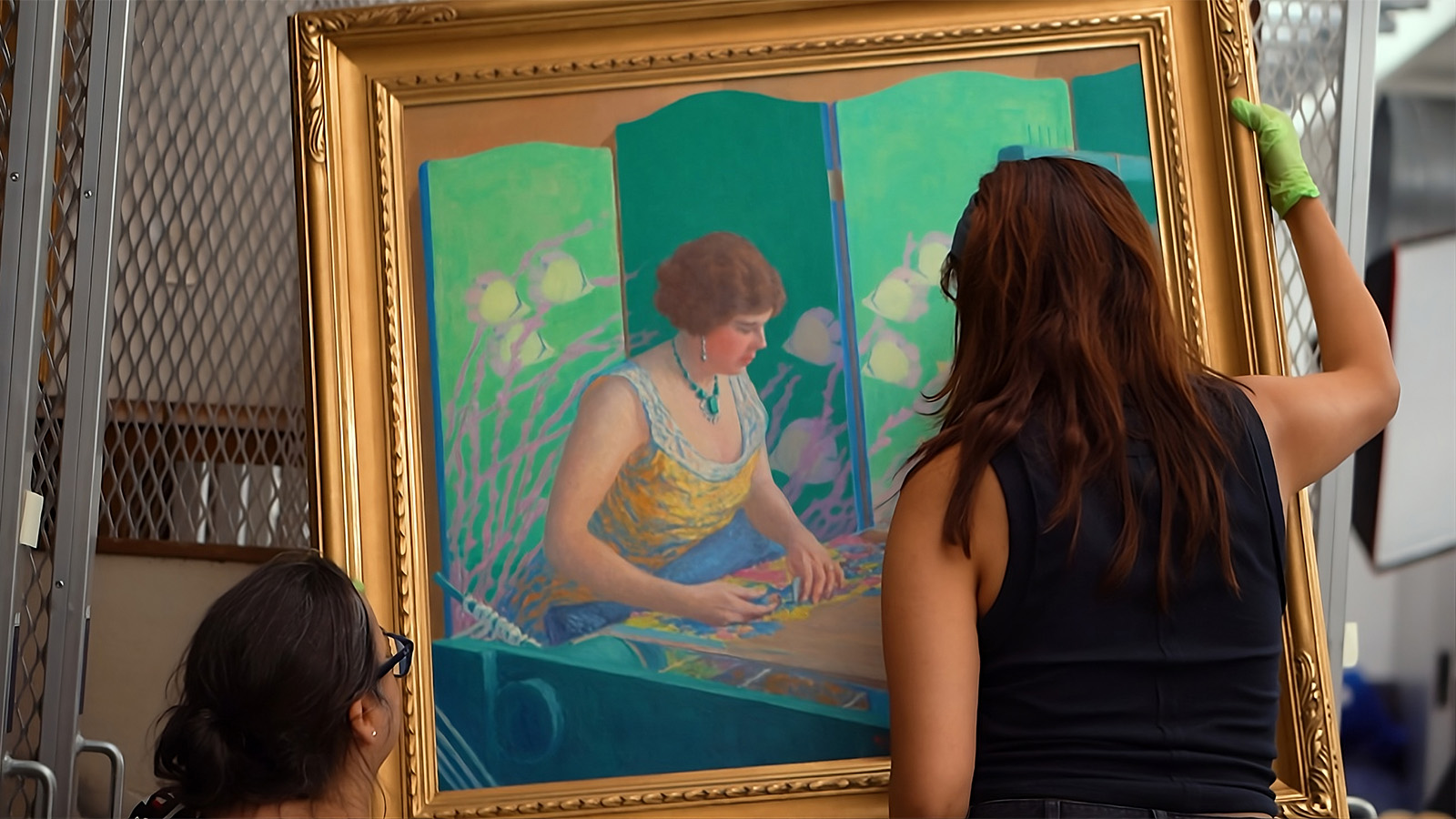 Assistant registrar Amy Silverman and registration intern Nicole Andrade remove a painting from a hanging rack.