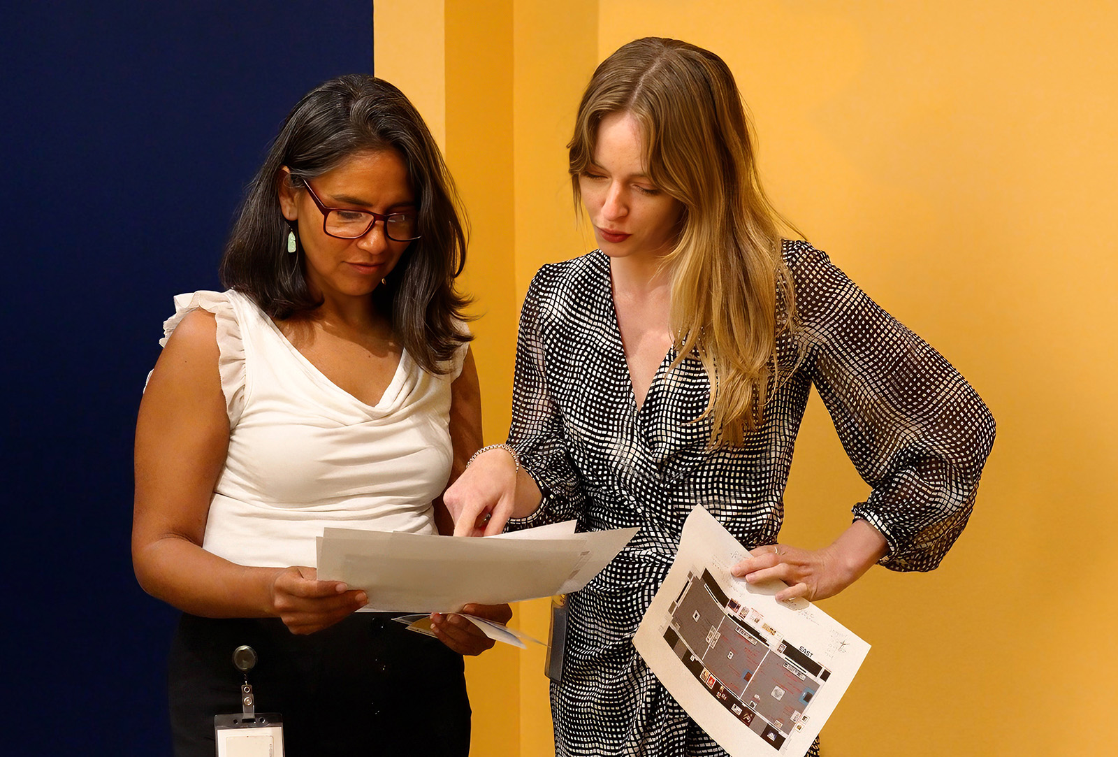 Silvia Manrique and Brittany Ballinger discussing floor plans for an upcoming exhibition.